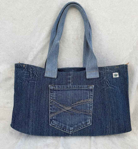 Blue denim tote bag with a pocket on a light gray background