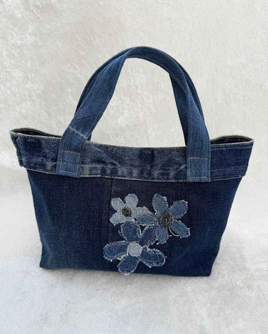 Denim handbag with floral appliqué on a white background