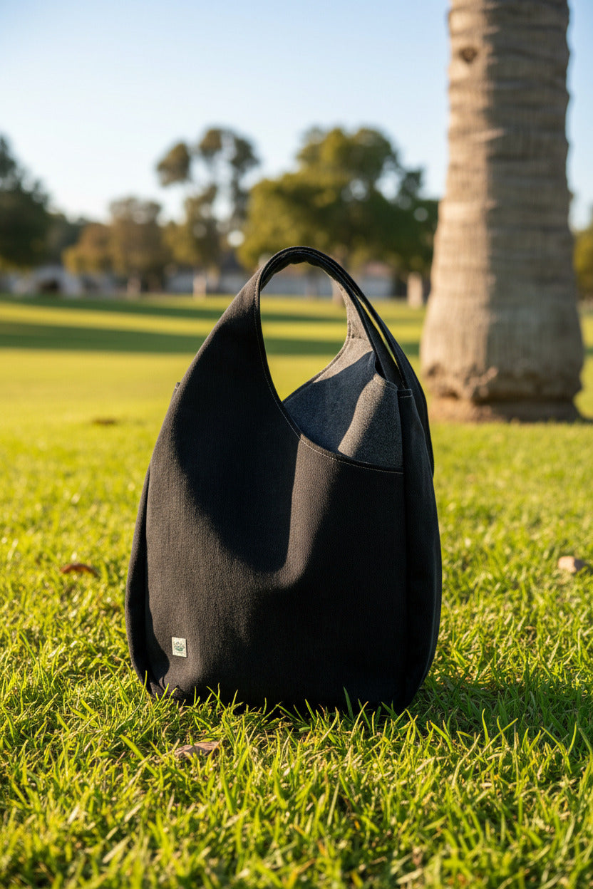 A large slouchy shoulder bag in dark charcoal and gray denim, featuring 2 large pockets where the "petals" overlap on both sides.